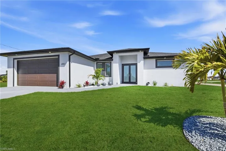 Prairie-style home with french doors, a front yard, stucco siding, and an attached garage