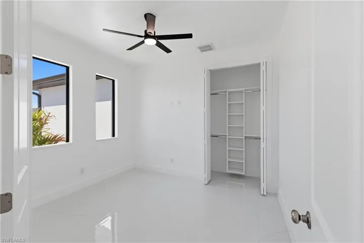 Unfurnished bedroom with light marble finish floors, a closet, and a ceiling fan