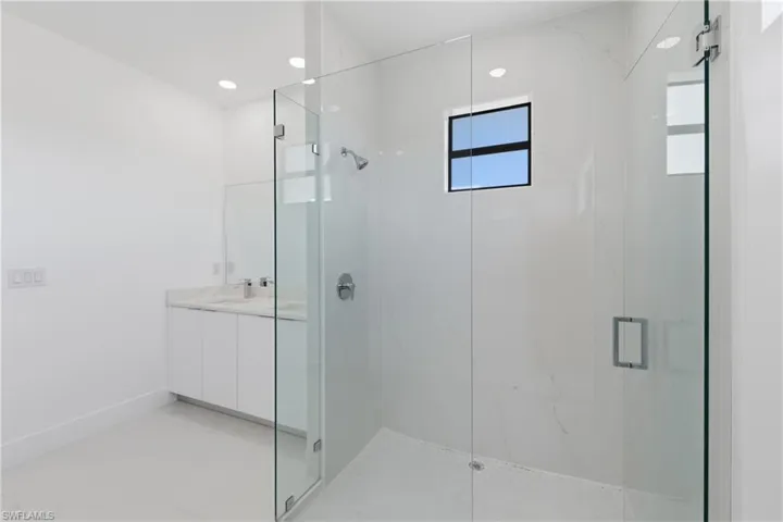 Full bathroom featuring a marble finish shower, vanity, and recessed lighting