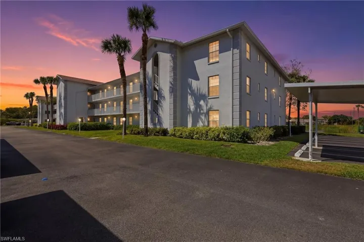 The property features a multi-story building with balconies, exterior lighting, and palm trees
