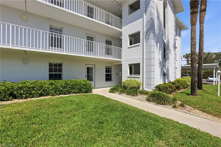 Exterior view of the property featuring a well-maintained lawn, established landscaping, and white balconies with railings