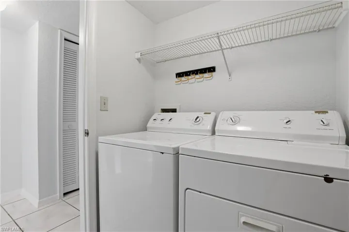 Dedicated laundry area featuring a white washer and dryer, a wire shelf, and tiled flooring