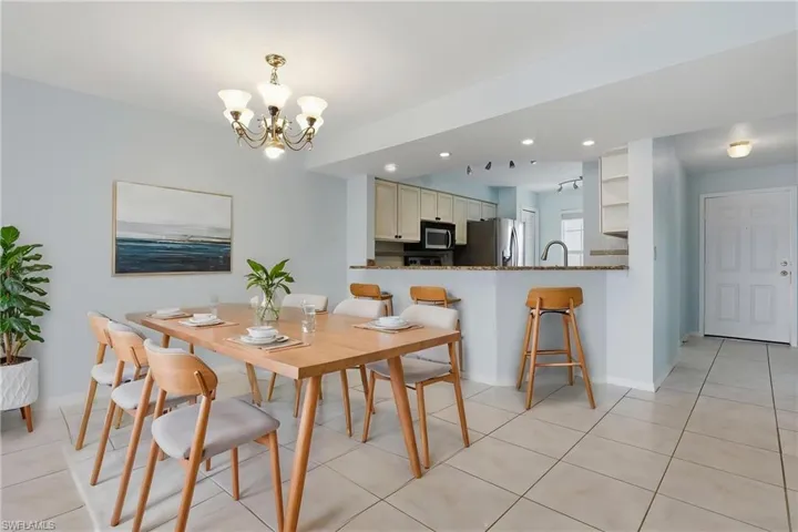 VIRTUALLY STAGED - Dining area featuring a chandelier, tile flooring, and a pass-through counter overlooking the kitchen