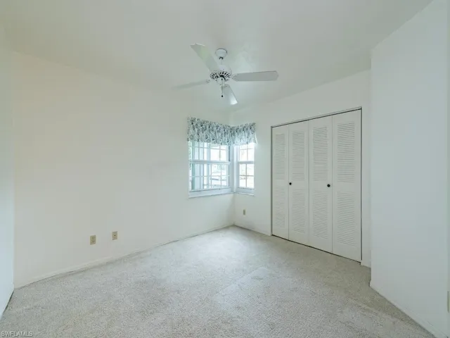Unfurnished bedroom featuring ceiling fan, a closet, and light colored carpet