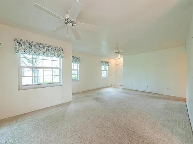 Empty room with ceiling fan and light carpet