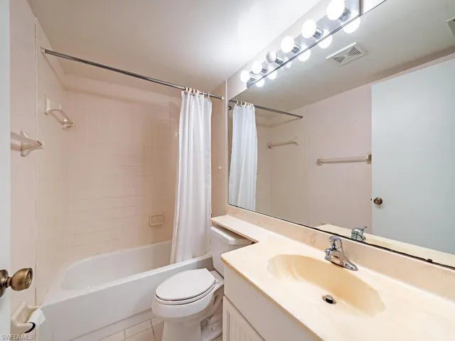 Full bathroom with tile floors, shower / bath combo, vanity, and toilet