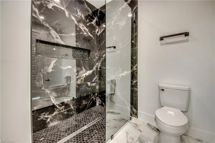 Bathroom with tiled shower, tile floors, and toilet
