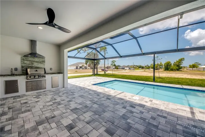 View of swimming pool with exterior kitchen, grilling area, a patio area, ceiling fan, and sink