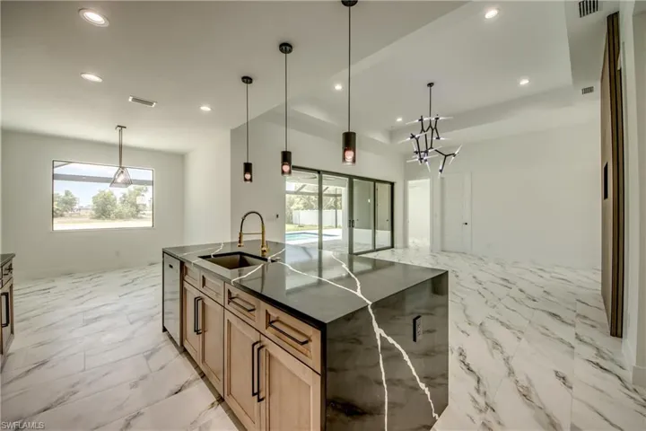Kitchen with stainless steel dishwasher, a kitchen island with sink, pendant lighting, sink, and light tile flooring
