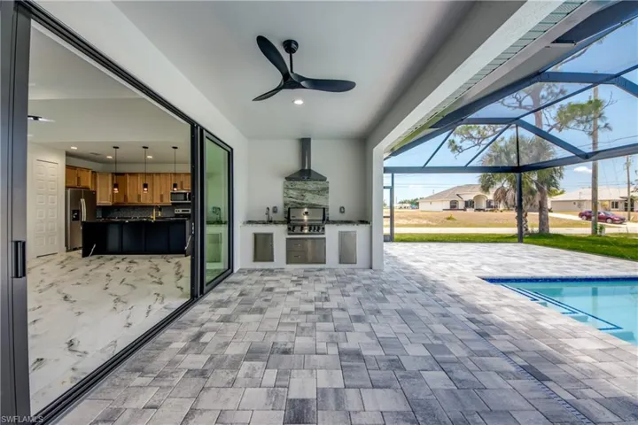 View of patio / terrace featuring area for grilling, glass enclosure, ceiling fan, and grilling area