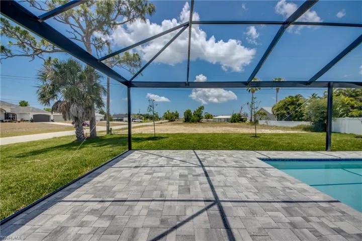 View of pool featuring glass enclosure, a patio area, and a lawn