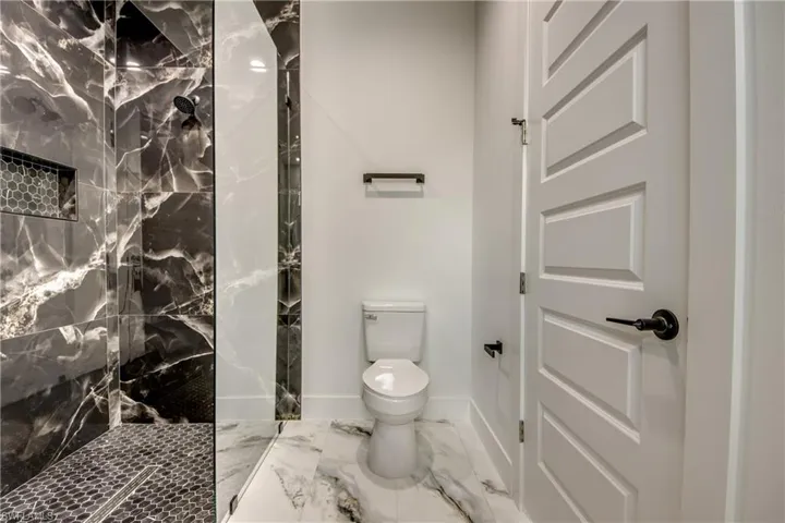 Bathroom with a tile shower, tile flooring, and toilet