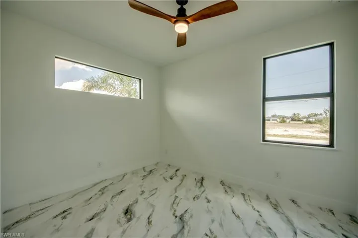 Tiled spare room featuring ceiling fan and a healthy amount of sunlight