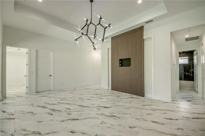 Unfurnished dining area with a notable chandelier, light tile floors, and a raised ceiling