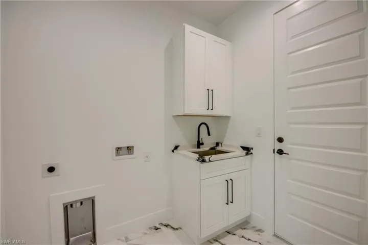 Laundry room featuring cabinets, hookup for a washing machine, sink, light tile floors, and hookup for an electric dryer