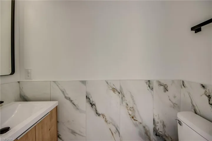 Bathroom featuring vanity, toilet, and tile walls