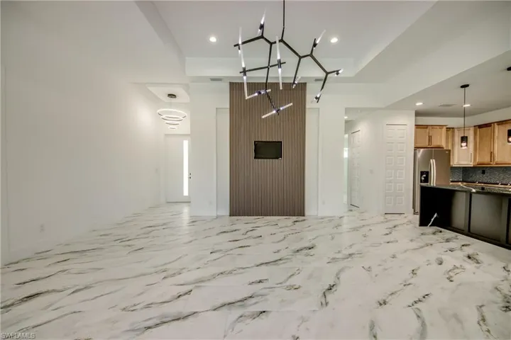 Kitchen featuring stainless steel fridge, tasteful backsplash, pendant lighting, a notable chandelier, and light tile floors