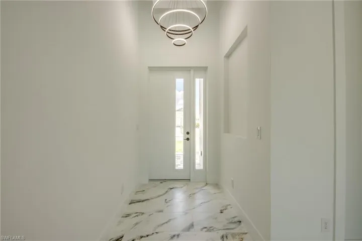 Foyer entrance with a notable chandelier and light tile flooring