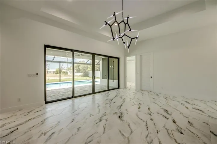 Tiled spare room featuring a notable chandelier and a raised ceiling
