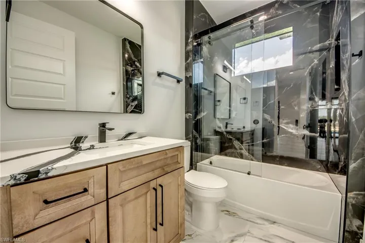 Full bathroom featuring tile flooring, bath / shower combo with glass door, toilet, and vanity