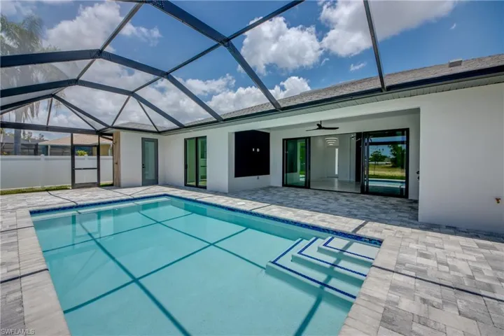 View of swimming pool with a patio, glass enclosure, and ceiling fan