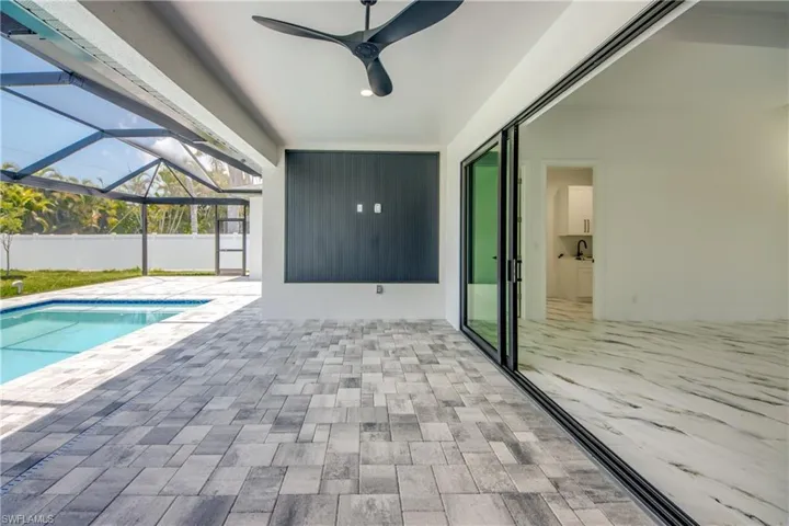 View of pool with a patio, glass enclosure, and ceiling fan