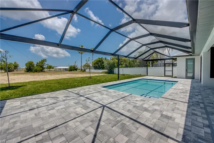 View of pool with a patio, glass enclosure, and a yard