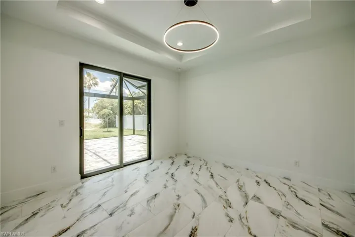 Unfurnished room featuring a tray ceiling and light tile floors