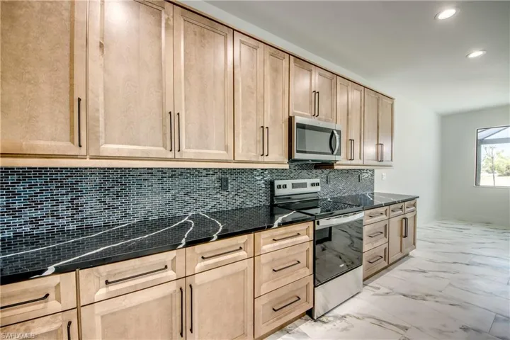 Kitchen featuring light brown cabinets, tasteful backsplash, light tile flooring, and stainless steel appliances