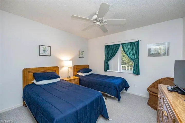 Carpeted bedroom with ceiling fan and a textured ceiling
