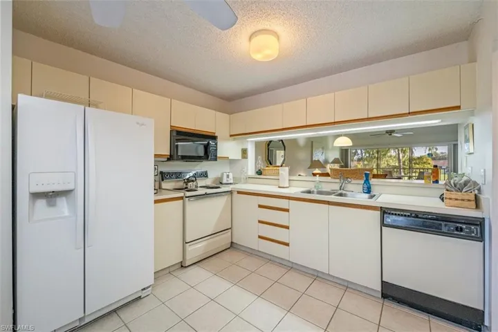 Kitchen with a ceiling fan, white appliances, light countertops, a textured ceiling, and light tile patterned floors
