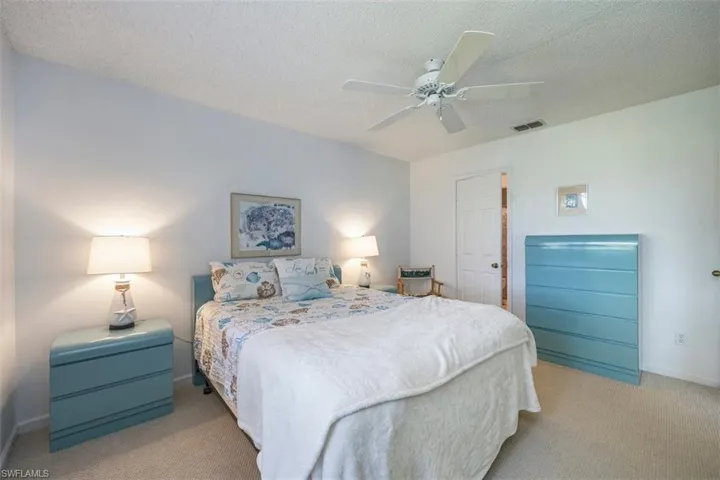 Carpeted bedroom with ceiling fan and a textured ceiling