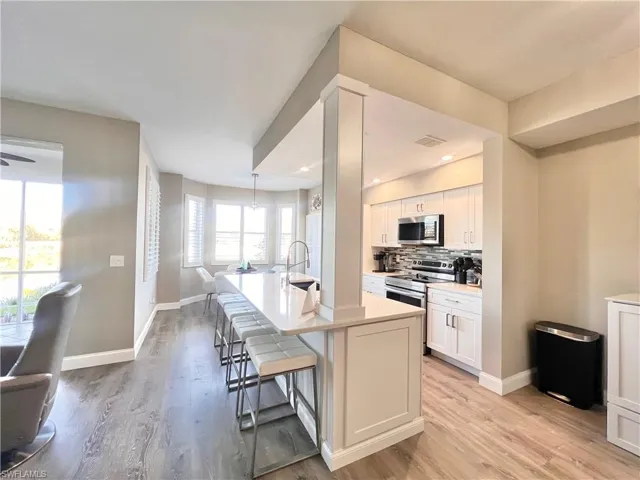 Kitchen featuring a breakfast bar area, backsplash, , and appliances Deluxe light gray vinyl flooring stainless steel finishes