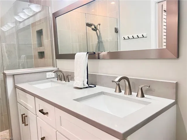 Bathroom featuring double vanity and a tile shower