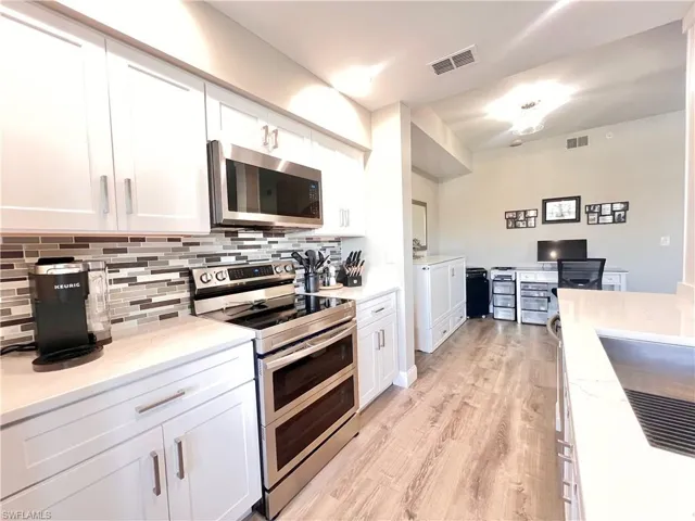Kitchen area featuring High end Samsung appliances,  New shaker cabinets, Quartz countertops, & light gray Deluxe Vinyl flooring
