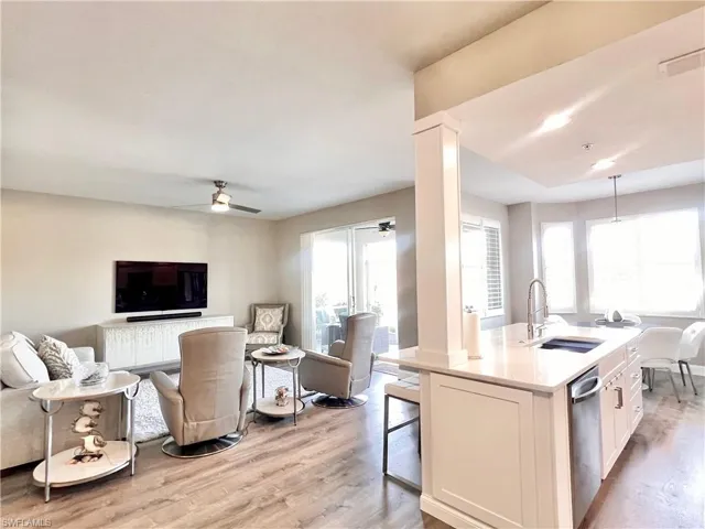 Kitchen with open floor plan, ceiling fan, an island with sink, Deluxe light gray vinyl flooring, and recessed lighting