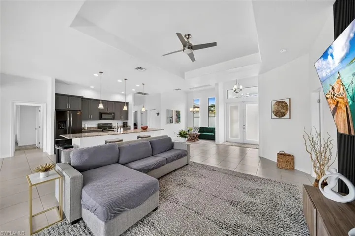 Open-concept living area featuring a vaulted ceiling with a ceiling fan, recessed lighting, and tile flooring