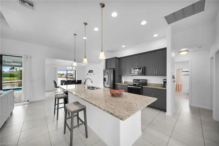 Spacious kitchen featuring a large island with a stone countertop, dark cabinetry, and integrated appliances