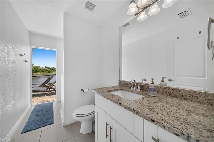 Bathroom vanity featuring a light-toned stone countertop with an integrated sink and chrome faucet
