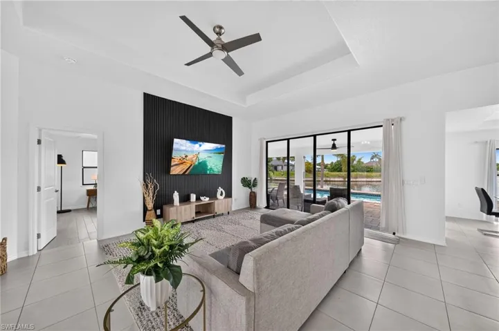 Spacious living area featuring a tray ceiling, contemporary ceiling fan, and large sliding glass doors