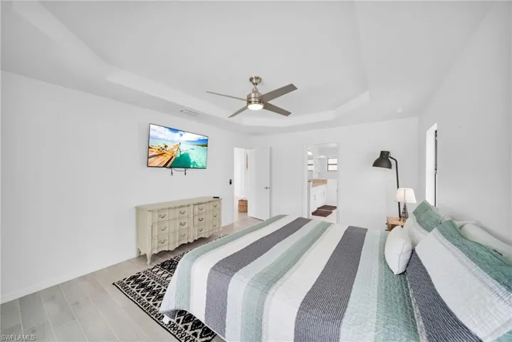 Recessed ceiling with a contemporary ceiling fan and light wood-finish flooring