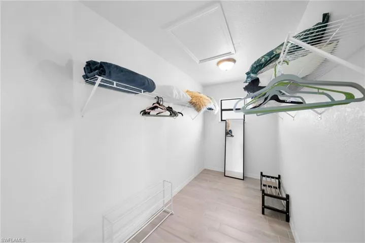 Walk-in closet featuring light wood-finish flooring, white walls, and built-in wire shelving