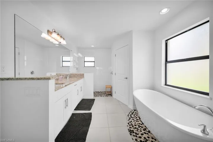 Well-appointed bathroom featuring a freestanding soaking tub with a pebble mosaic accent