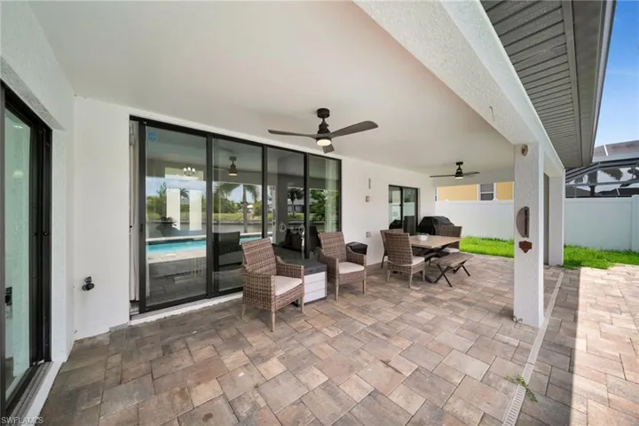 Covered patio featuring a paver surface, ceiling fans, and sliding glass doors