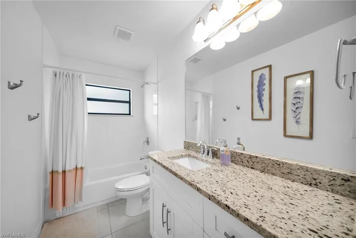 Bathroom featuring a white vanity with slab countertop, undermount sink, and chrome fixtures