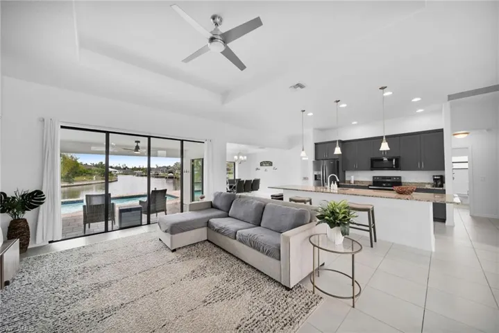 Open concept living area with tray ceiling and ceiling fan