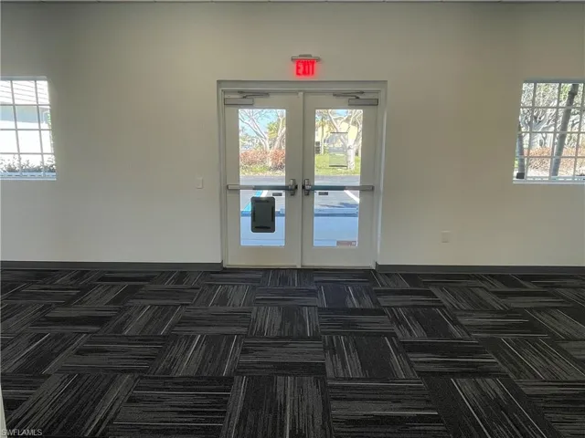 Hallway with dark colored carpet and baseboards