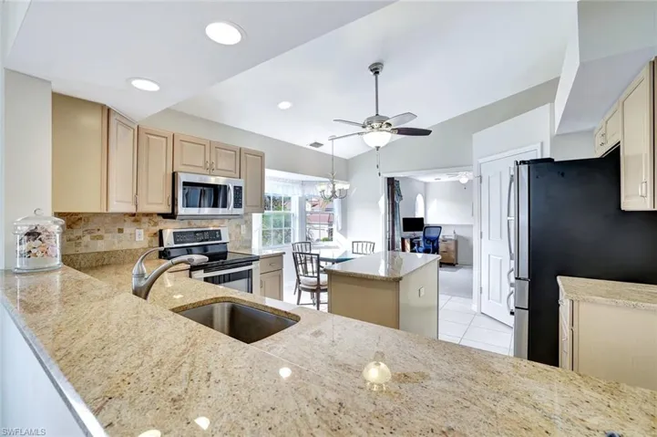 Kitchen with stainless steel appliances, granite countertops, ceiling fan, a kitchen island and dining area.