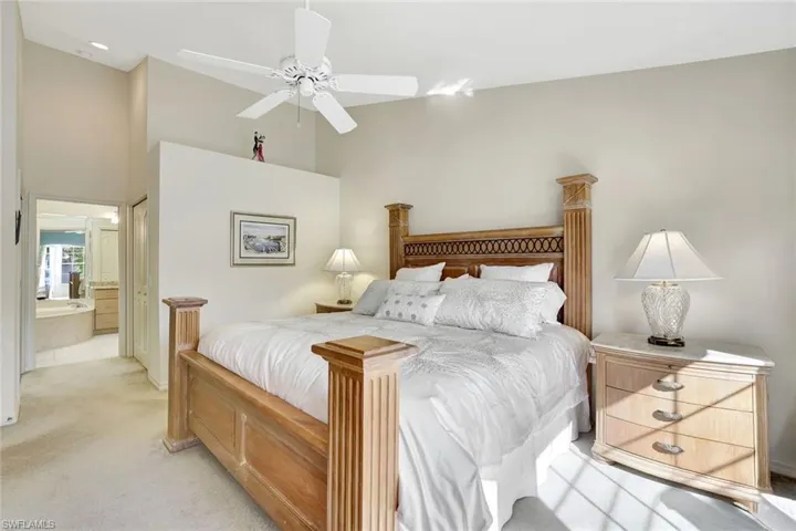 Sunlit primary bedroom featuring  ensuite bathroom, a towering ceiling, ceiling fan, and a walk-in closet and second closet.