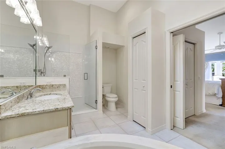 Primary ensuite bathroom featuring granite vanity tops, a linen closet, a newly renovated shower stall and glass door, new lighting.
